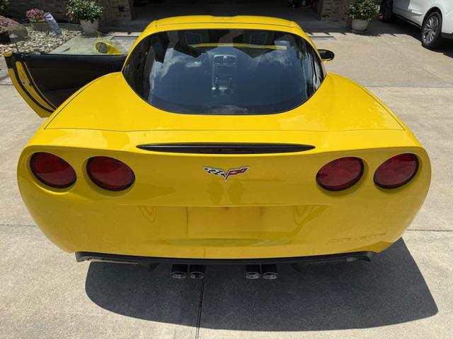 Rear view of a yellow Corvette C6 in a driveway after exterior detail, with glossy paint and clean taillights