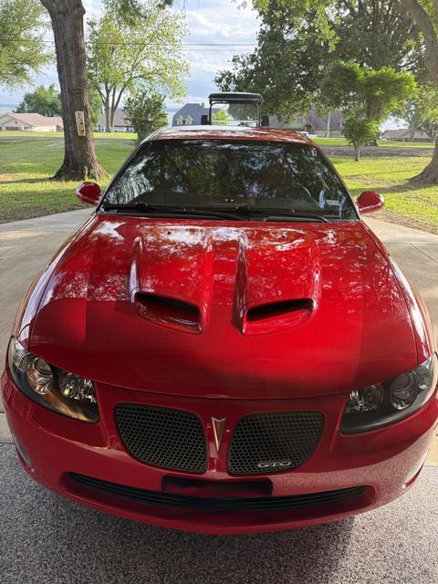 Front view of a red Pontiac GTO coupe after exterior detail, with glossy paint and clean hood scoops